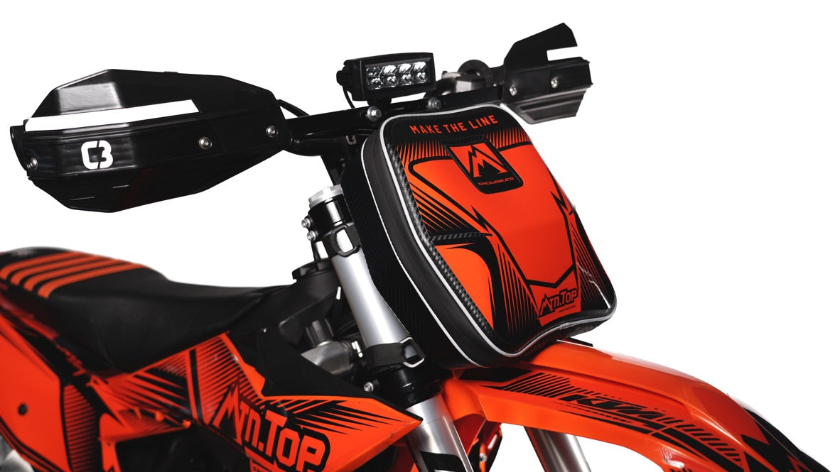 MTN.TOP Number Plate Bag with orange graphic kit mounted on the front of a snowbike