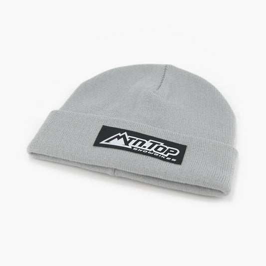 A silver knit beanie hat featuring a black rectangular patch on the folded cuff with the white 'MTN.TOP Snowbikes logo, set against a plain white background.