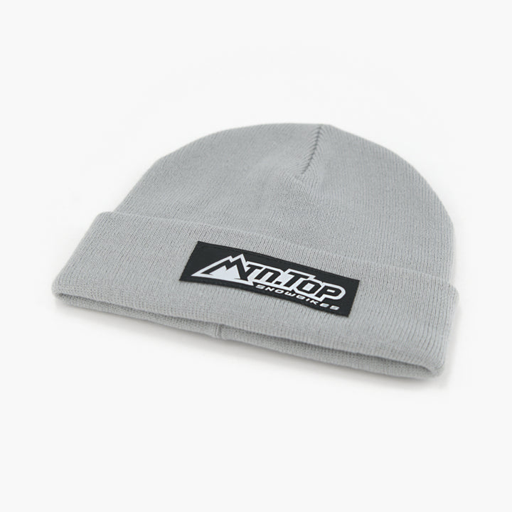A silver knit beanie hat featuring a black rectangular patch on the folded cuff with the white 'MTN.TOP Snowbikes logo, set against a plain white background.