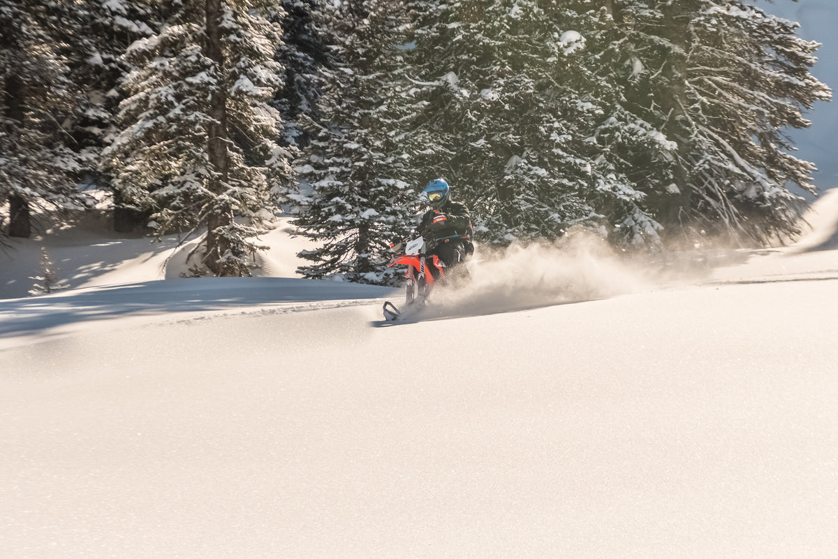 MTN.TOP snowbike rider kicking up fresh powder on a sunny mountain slope